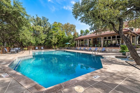 a swimming pool with trees and a house in the background