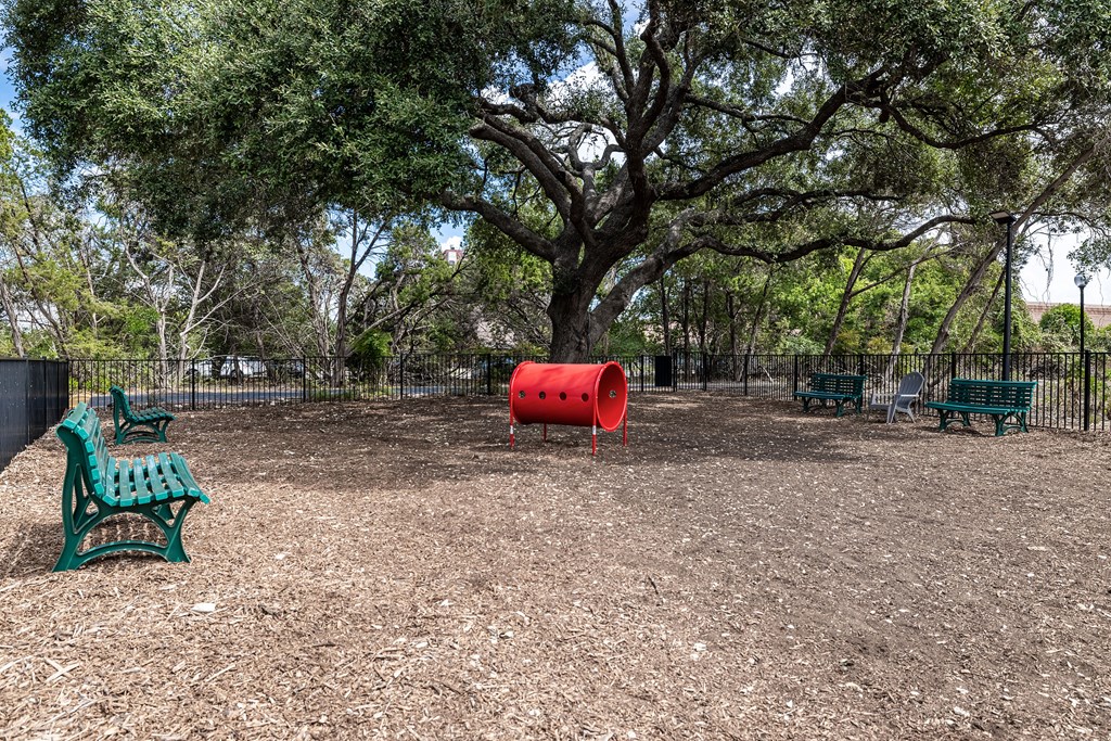 a playground with benches and a red barrel