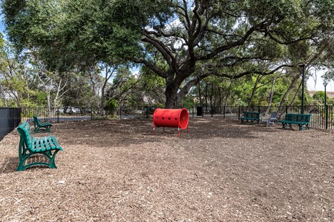 a playground with benches and a red barrel