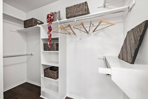 a walk in closet with baskets and hangers on the wall