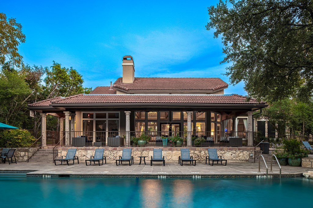 the back of the house has a pool and patio with chairs