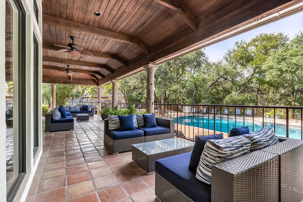 a covered patio with furniture and a swimming pool