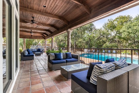 a covered patio with furniture and a swimming pool