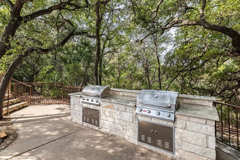 a stone outdoor kitchen with two stainless steel appliances