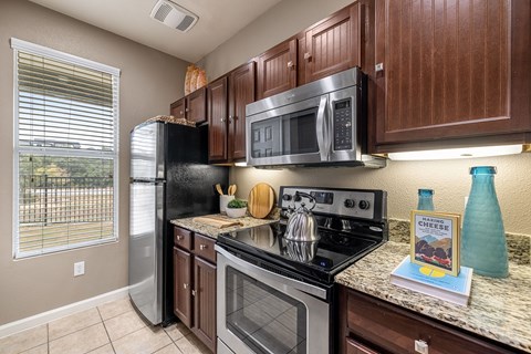 A kitchen with brown cabinets and a black fridge.