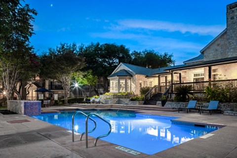a swimming pool with lounge chairs and umbrellas in front of a brick building