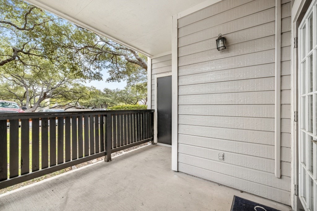 a balcony with a door and a view of a tree and a parking lot