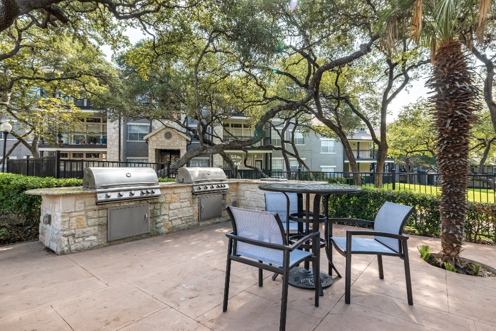 a patio with a grill and a table and chairs