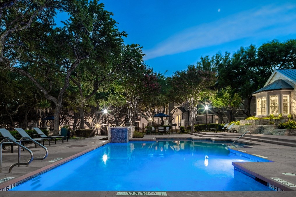 a swimming pool with trees and a building in the background