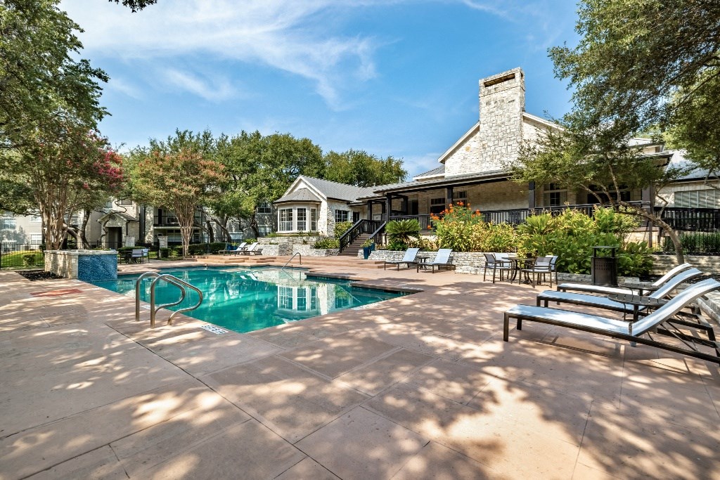 a swimming pool with lounge chairs and a house in the background