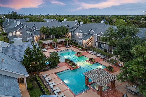 A swimming pool surrounded by a brick patio and lounge chairs.