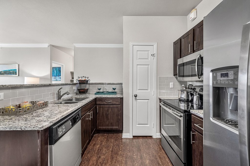 an empty kitchen with stainless steel appliances and granite counter tops