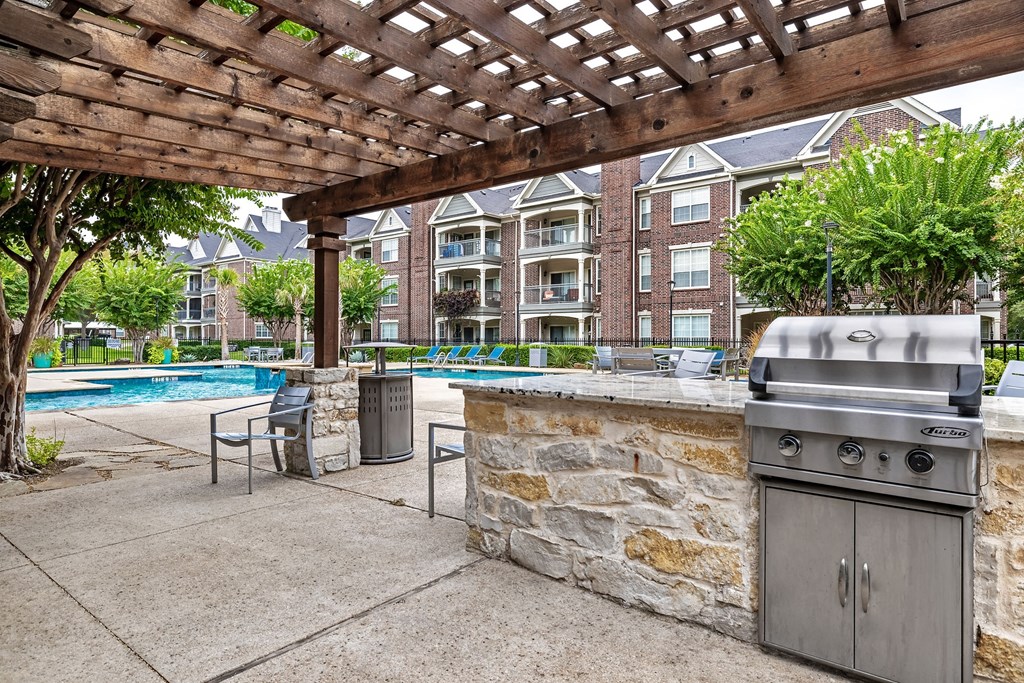 a patio with a grill and a pool with a building in the background