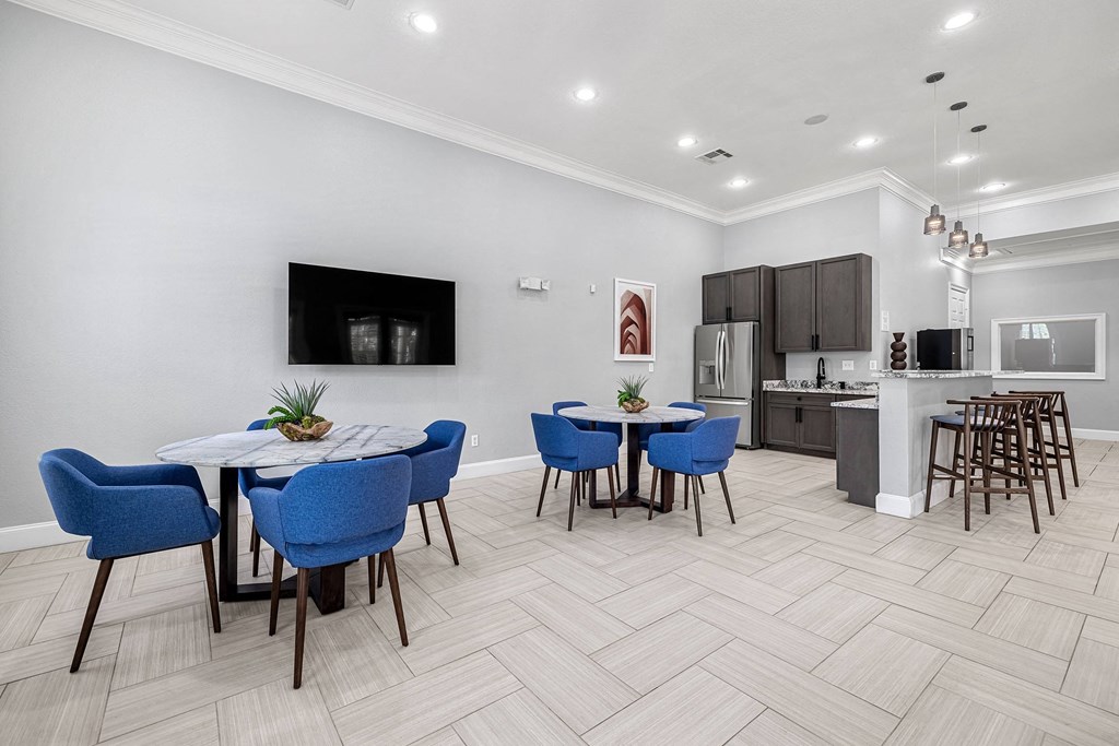 a dining area with a table and chairs and a kitchen in the background