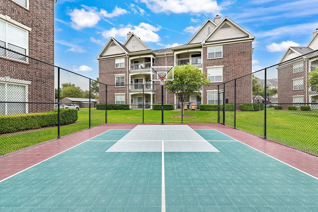 a tennis court in front of an apartment building