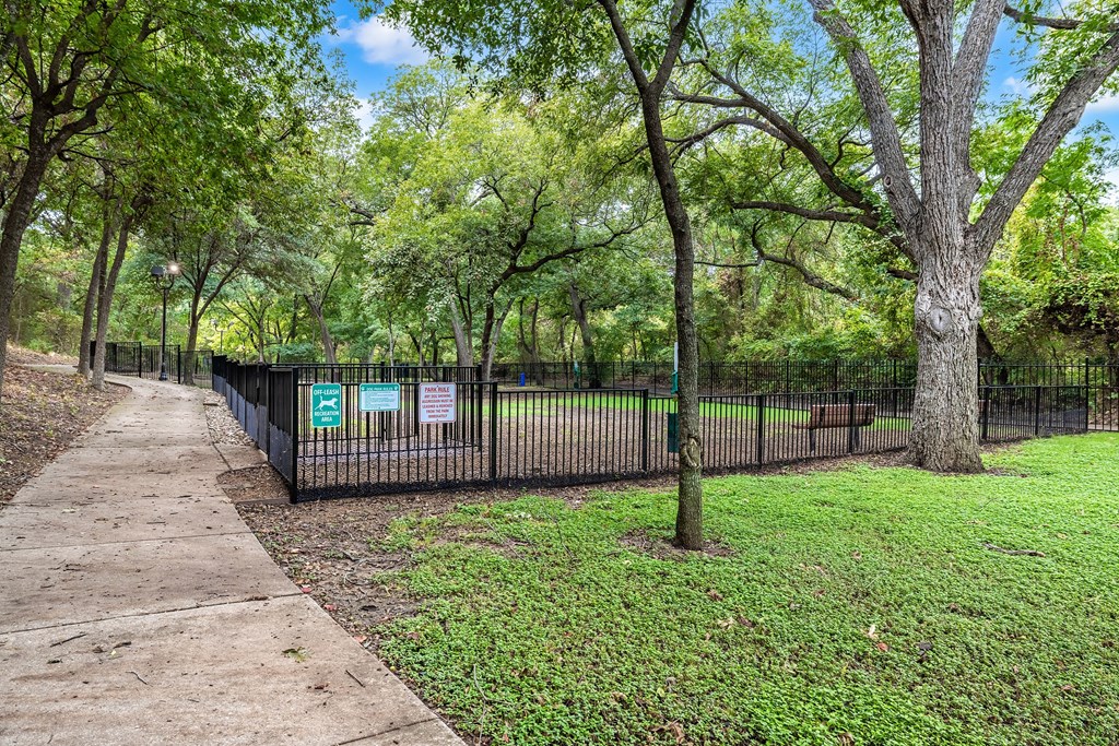 a park with a fence and trees and a sidewalk