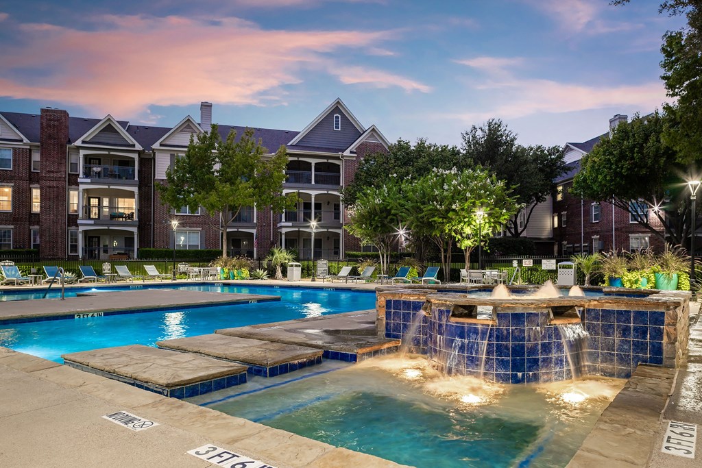 a swimming pool with a fountain in front of an apartment building