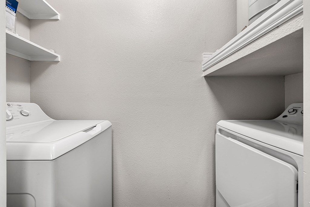 the laundry room has a washer and dryer and a shelf above the sink