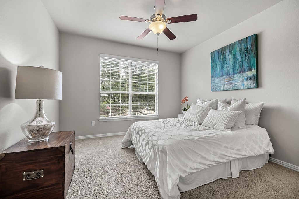 an empty bedroom with a bed and a ceiling fan
