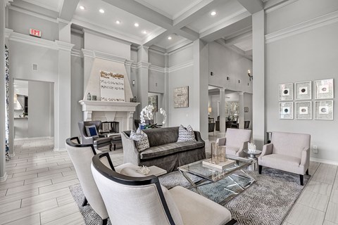 A living room with a grey couch and a glass coffee table.