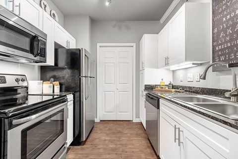 A kitchen with white cabinets and black appliances.