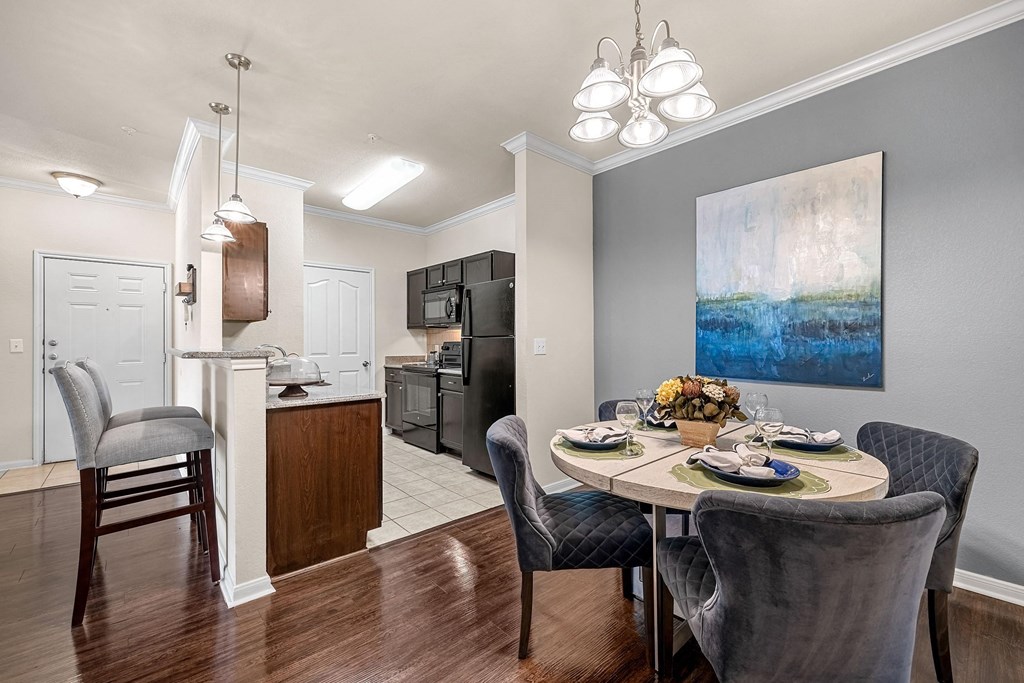 a dining area with a table and chairs and a kitchen in the background