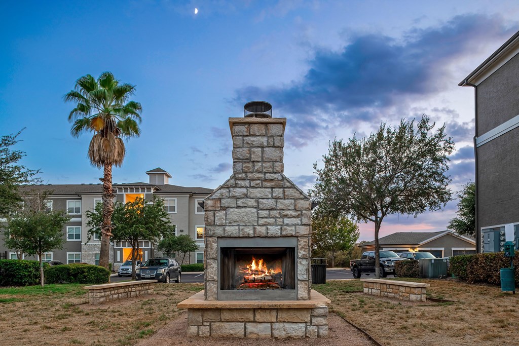 a stone fireplace with a stone bench in front of it and a palm tree in the background