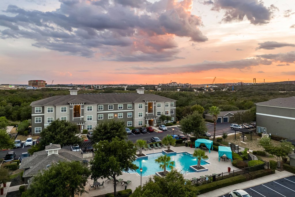 an aerial view of a large swimming pool with a sunset in the background
