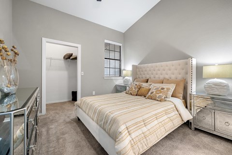 A bedroom with a bed, nightstand, and a dresser with a mirror.