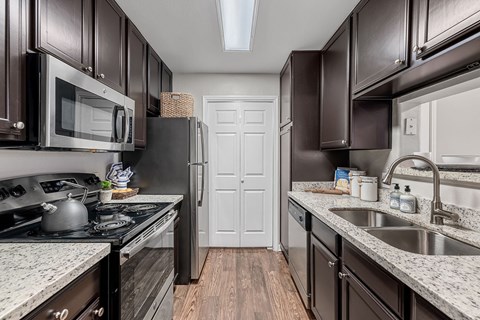 A kitchen with dark brown cabinets and a white door in the background.