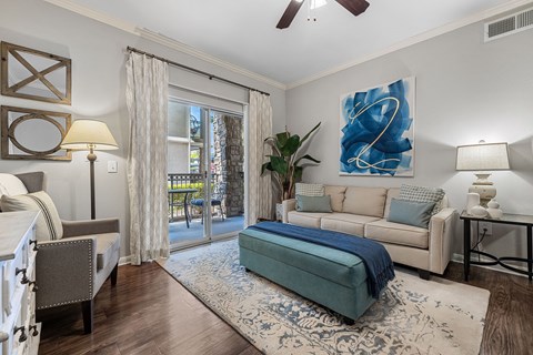 A living room with a blue couch and a painting on the wall.