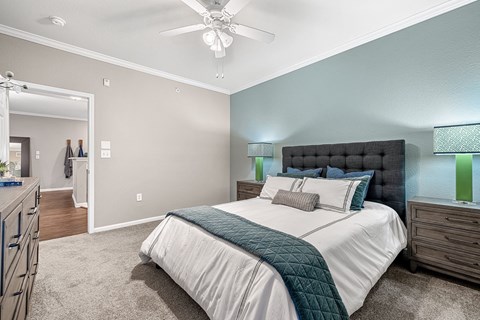 A bedroom with a large bed and a ceiling fan.