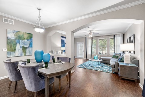 A dining room with a table set for two and a couch in the background.