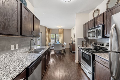 A kitchen with dark wood cabinets and stainless steel appliances.