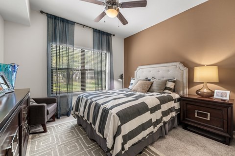 the master bedroom has a large window and a comfy bed