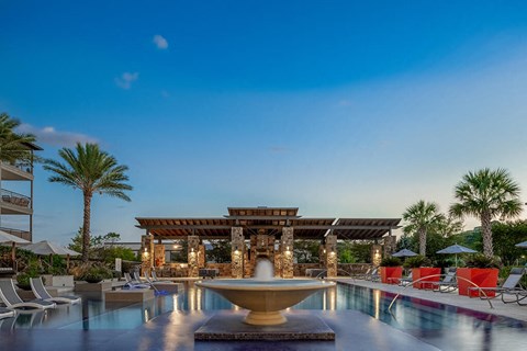 A luxurious poolside setting with a fountain at the center.