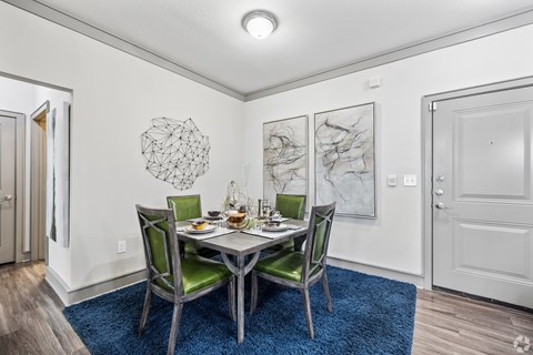 A dining room with a table set for two and a blue rug.