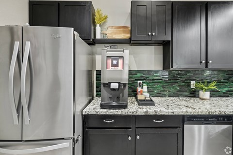 A modern kitchen with a stainless steel refrigerator and black cabinets.
