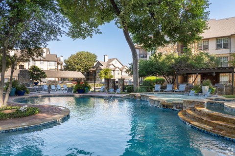 A large swimming pool surrounded by trees and lounge chairs.