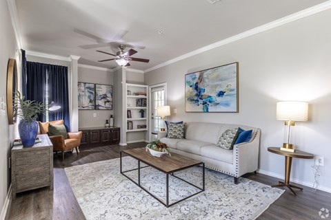 A living room with a white couch, a coffee table, and a painting on the wall.