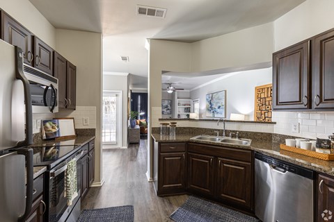 A kitchen with dark wood cabinets and a stainless steel dishwasher.
