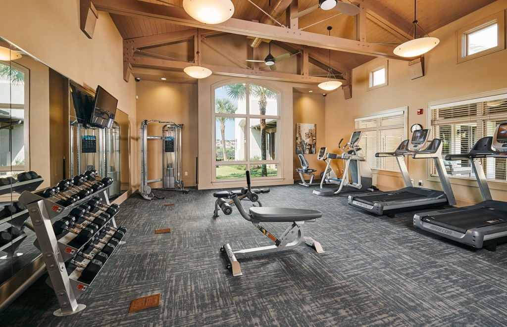 A spacious gym with a variety of equipment including treadmills, weight machines, and a bench press.