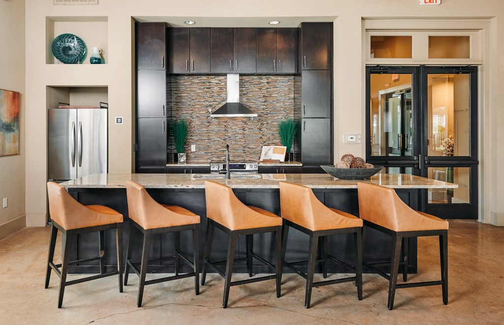 A kitchen with a black counter and brown chairs.
