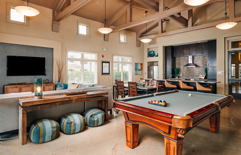 A billiards table is in the middle of a room with a couch and a television.