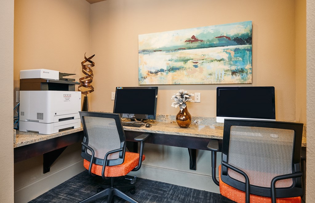 A room with two chairs and a desk with a computer on it.