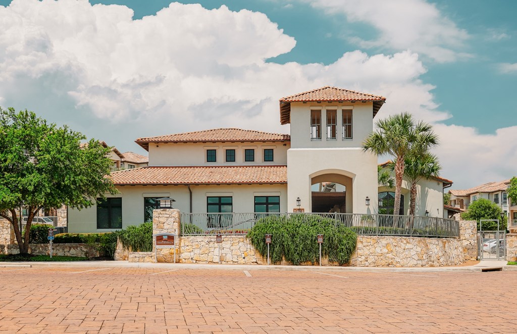 A large house with a stone wall and a red tile roof.