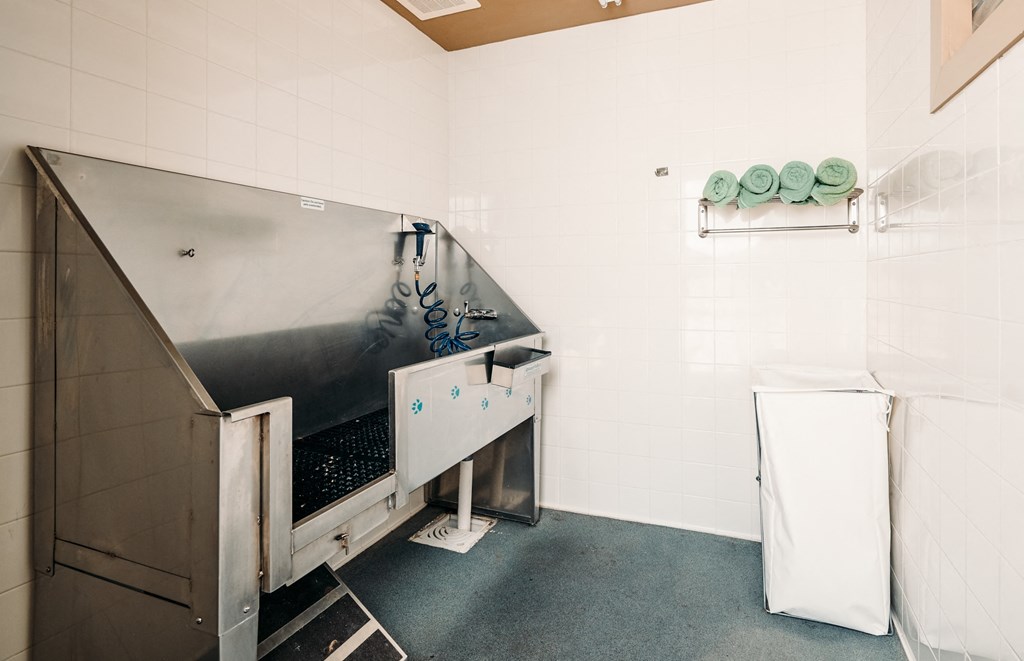 A cleaning cart with a white bag is in a room with a metal wall.