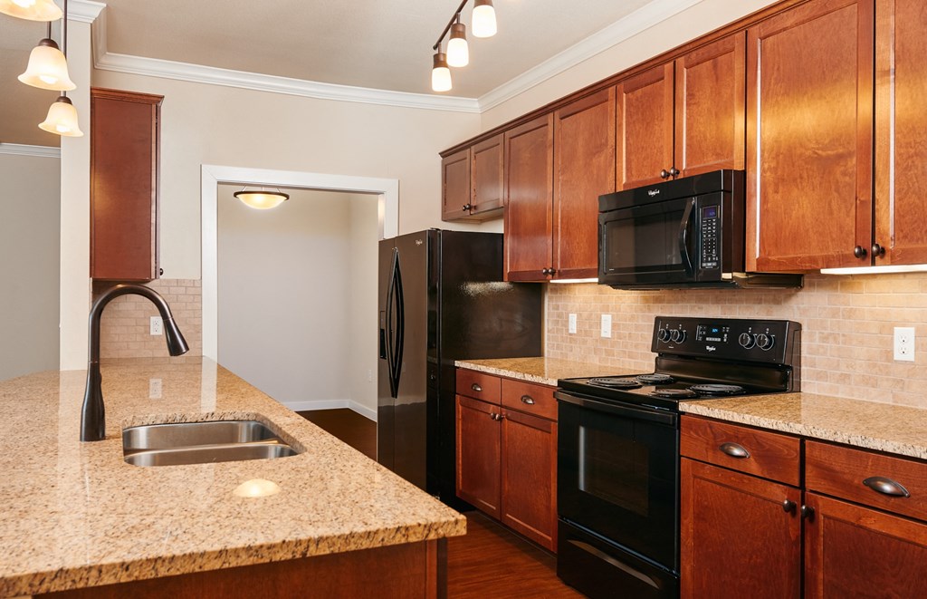 A kitchen with wooden cabinets and black appliances.