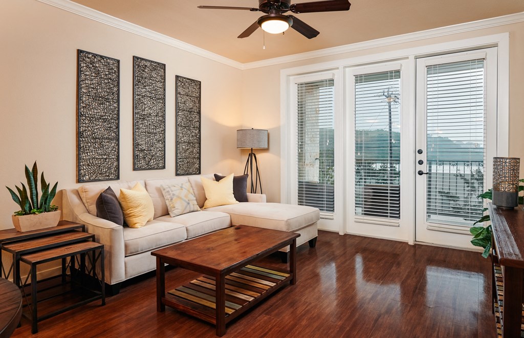 A living room with a white couch, a wooden coffee table, and a ceiling fan.