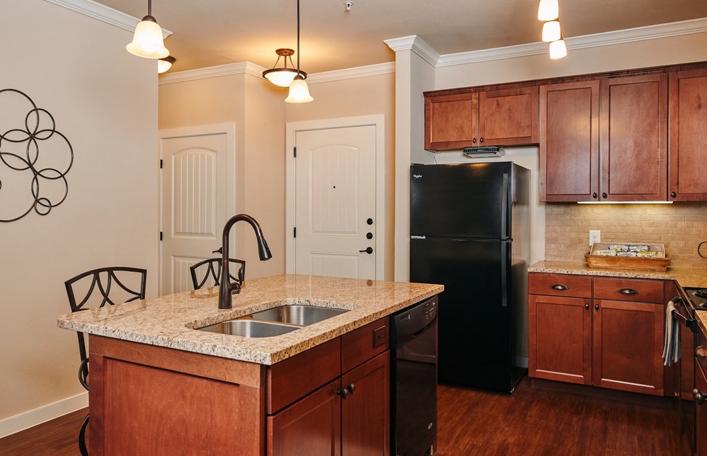 A kitchen with a black refrigerator and wooden cabinets.